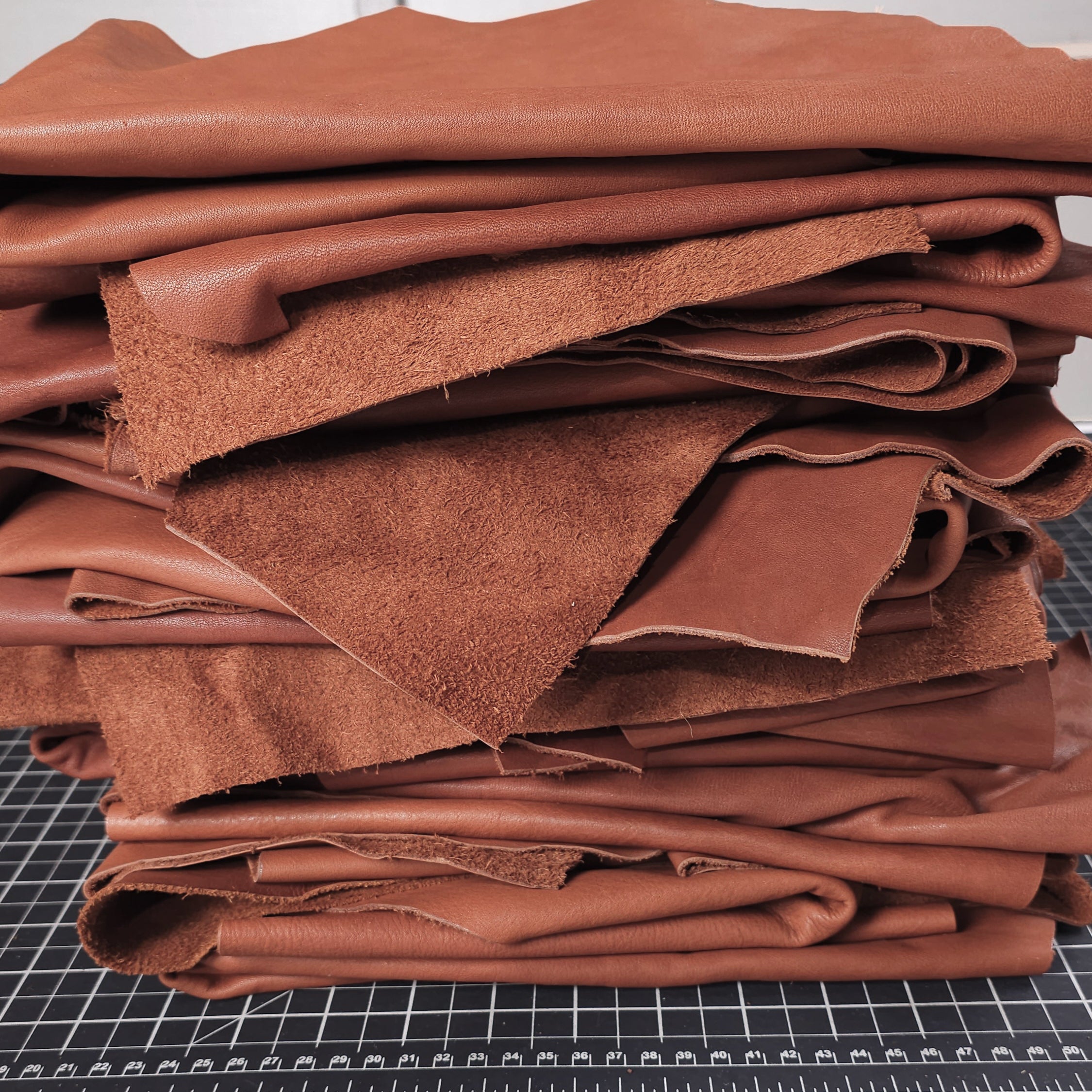 Brown veg tan leather pieces stacked on cutting mat