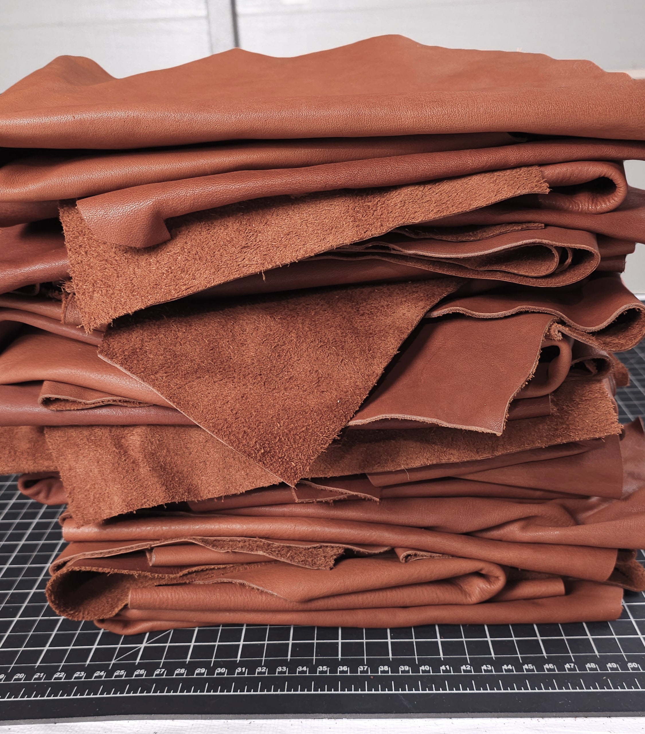 Brown veg tan leather pieces stacked on cutting mat