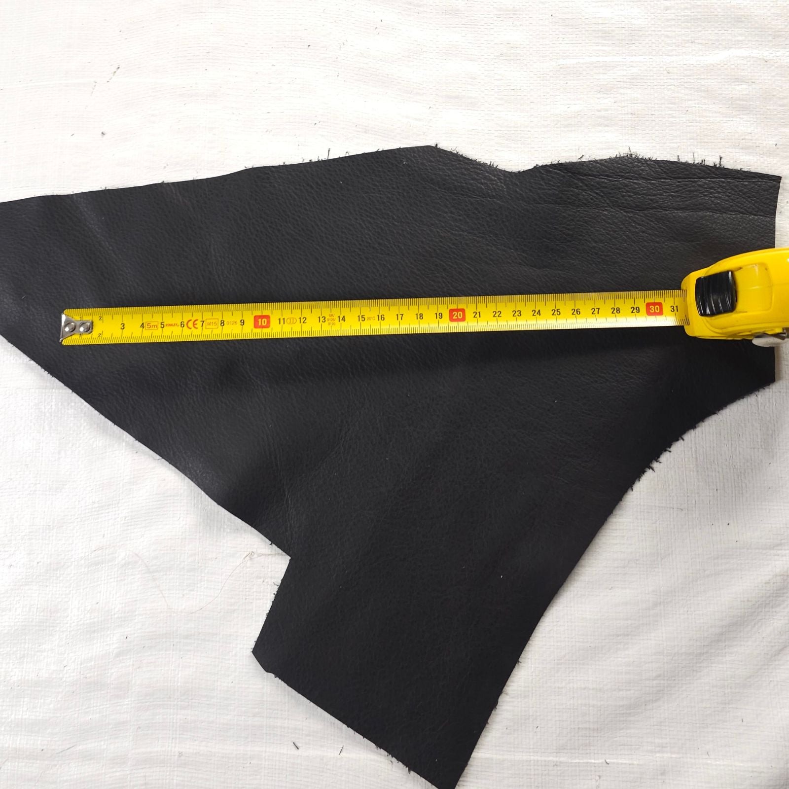 Black leather offcut shown with measuring tape for size