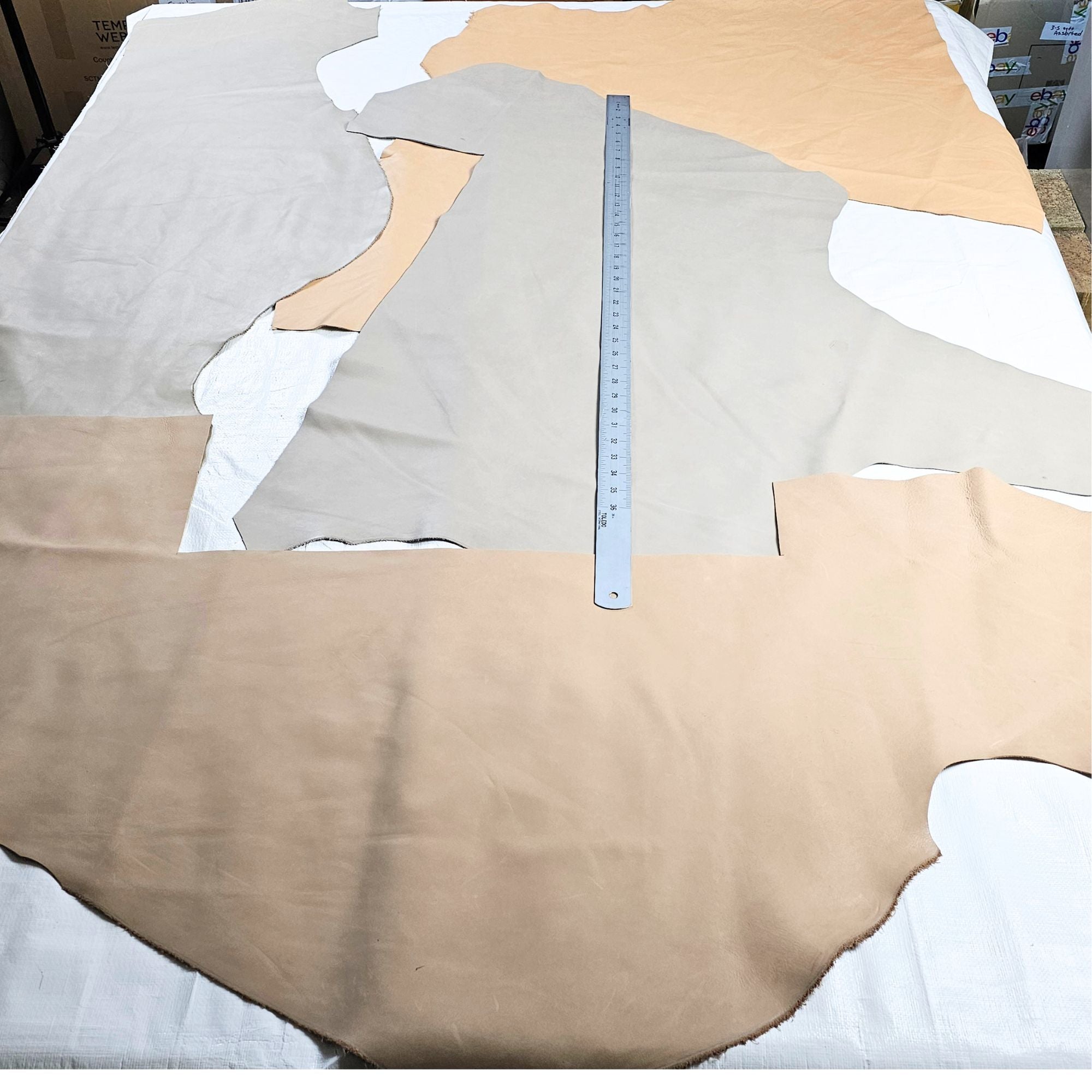 Large light neutral leather offcuts shown with measuring tape
