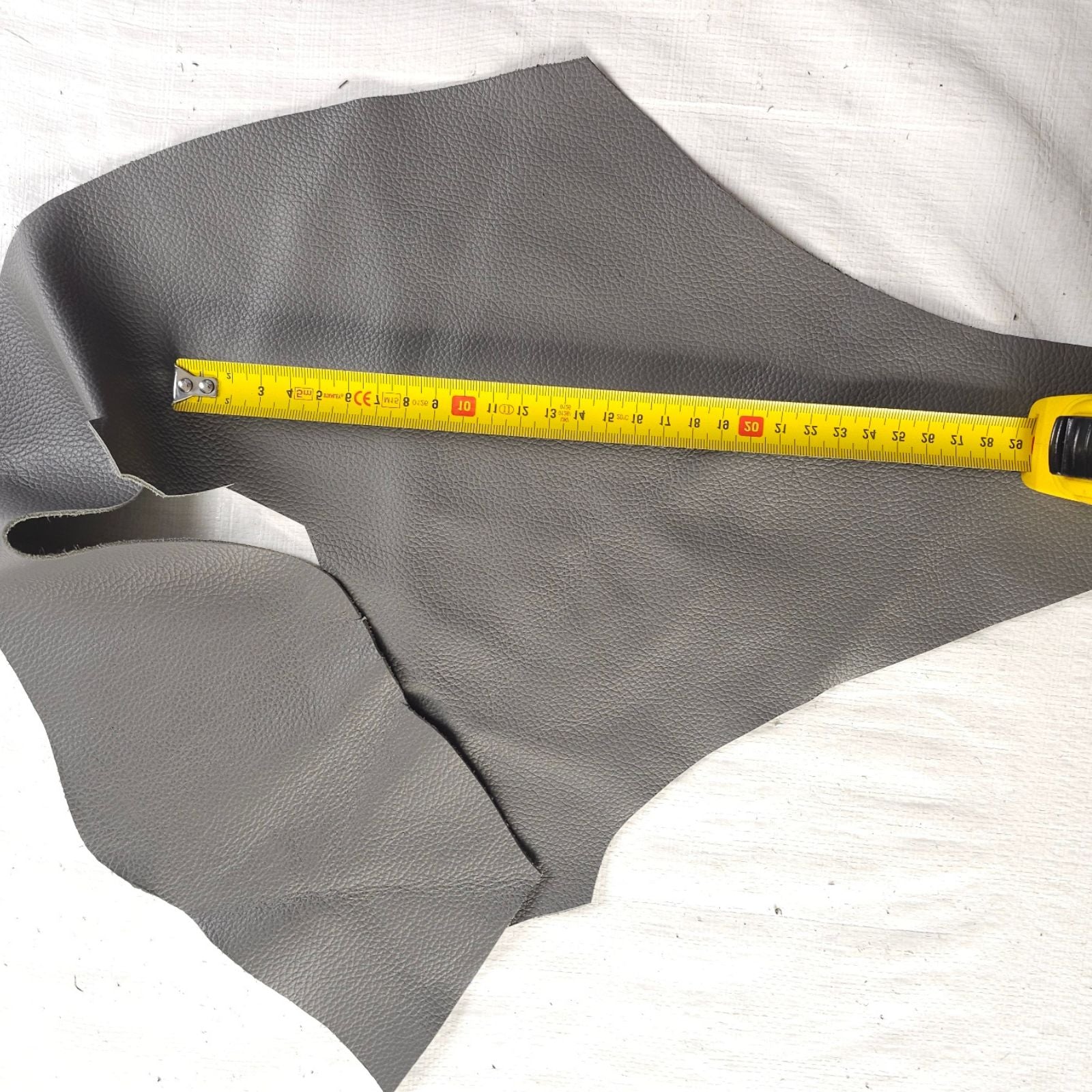 Grey irregular leather piece shown with measuring tape