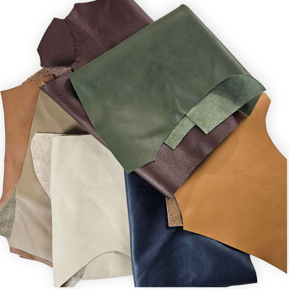 A stack of leather scraps, including olive green, dark brown, tan, cream, and navy blue.