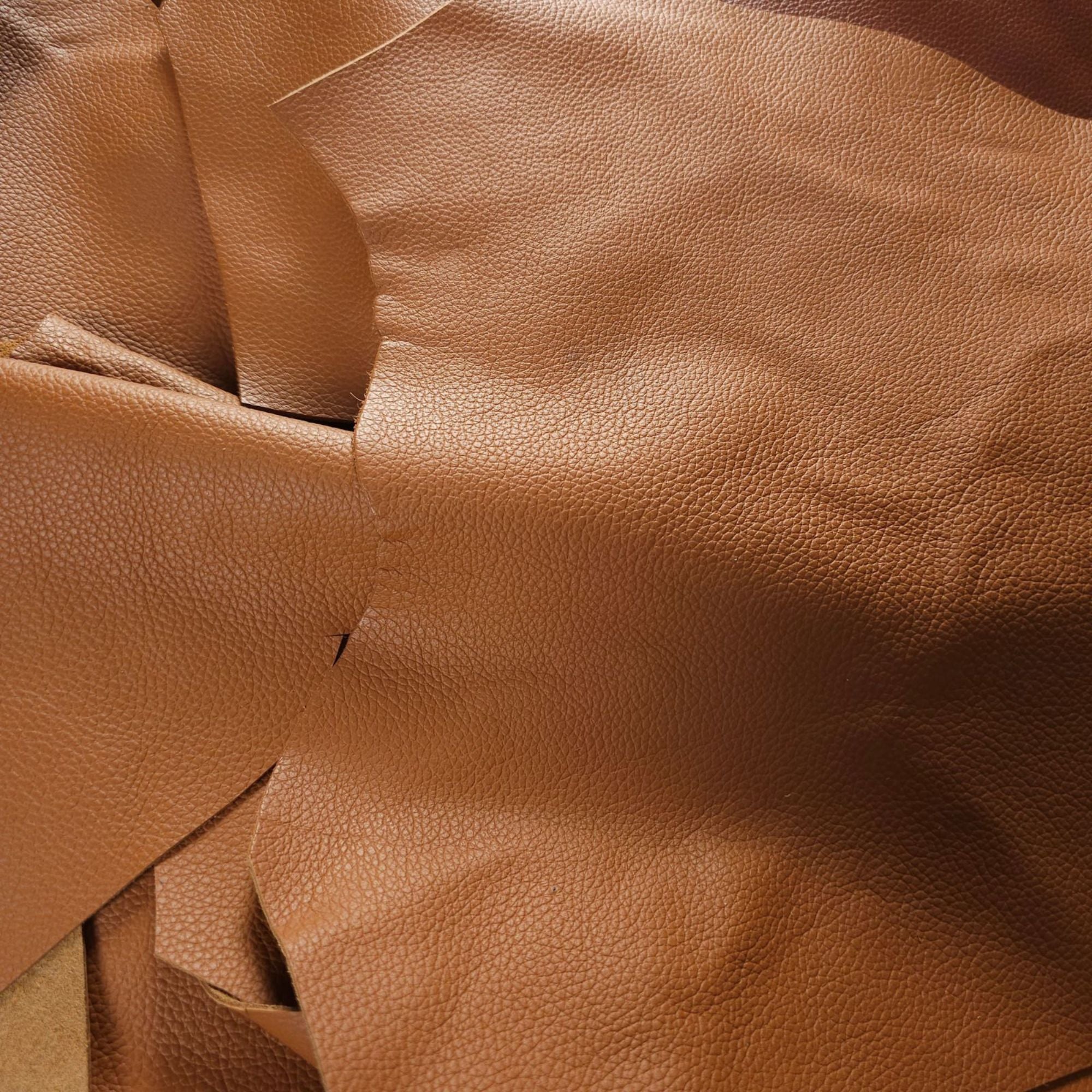 Tan corrected-grain cowhide leather scraps showing textured finish